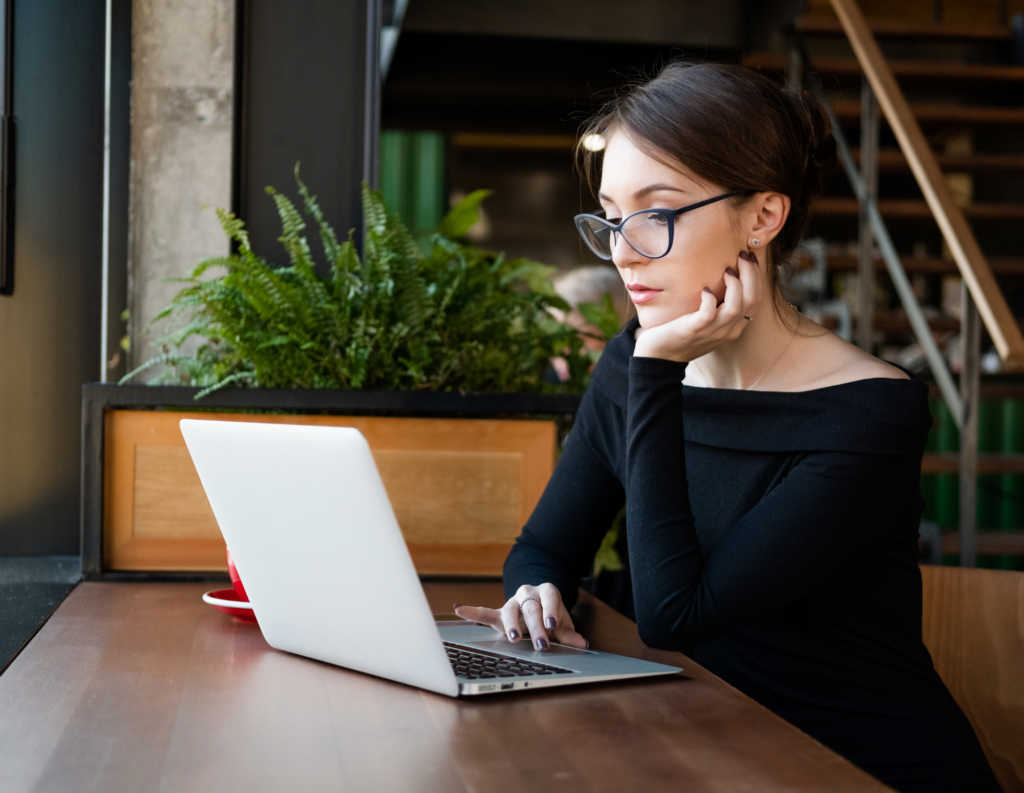 writing-reminder-email-for-payment Woman thinking at her computer as she writes an email.